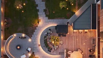 An aerial view of a rooftop patio with circular seating areas, a pool, and a dining area with umbrellas.
