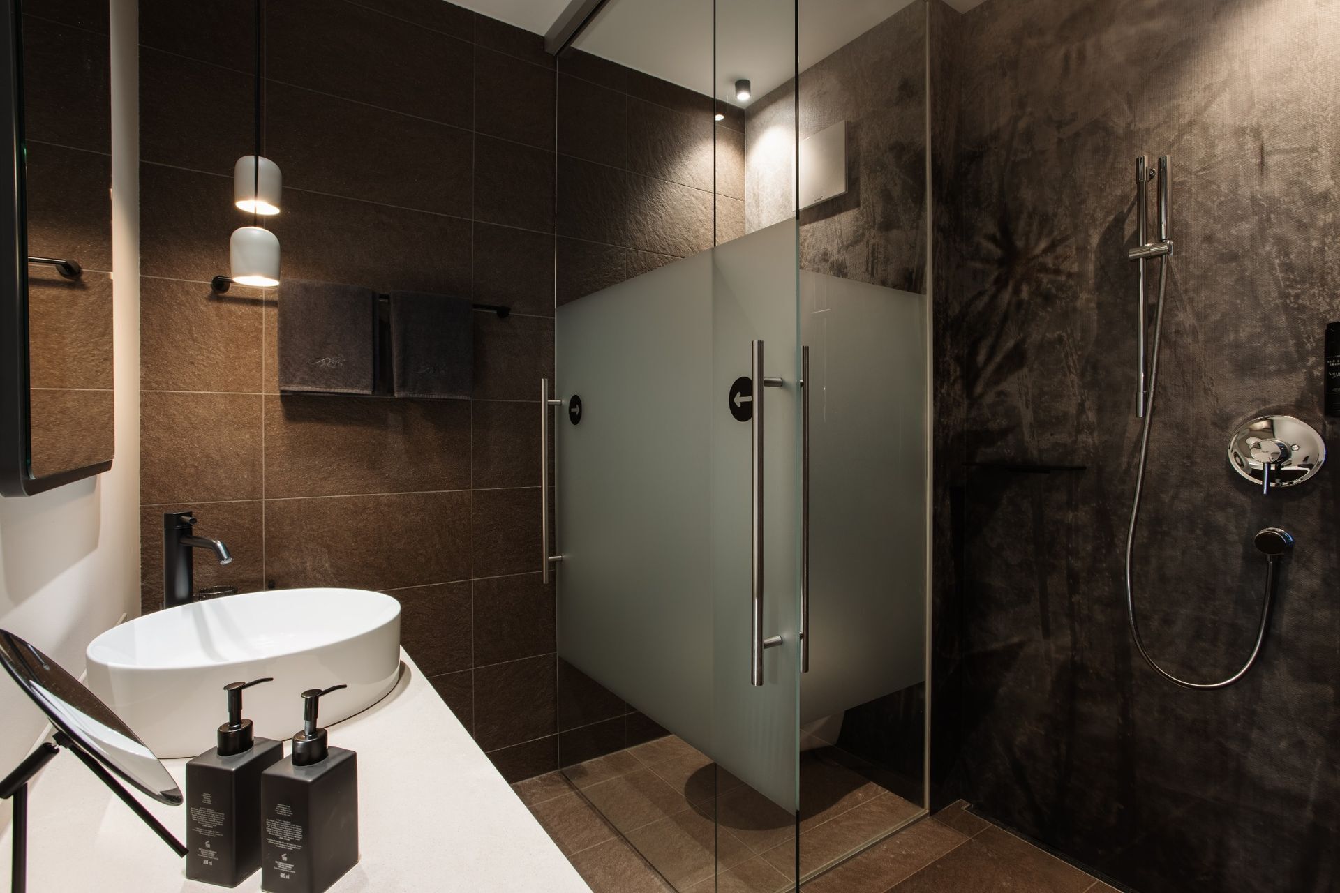 Un baño moderno con cabina de ducha de vidrio, un lavabo blanco y un espejo.