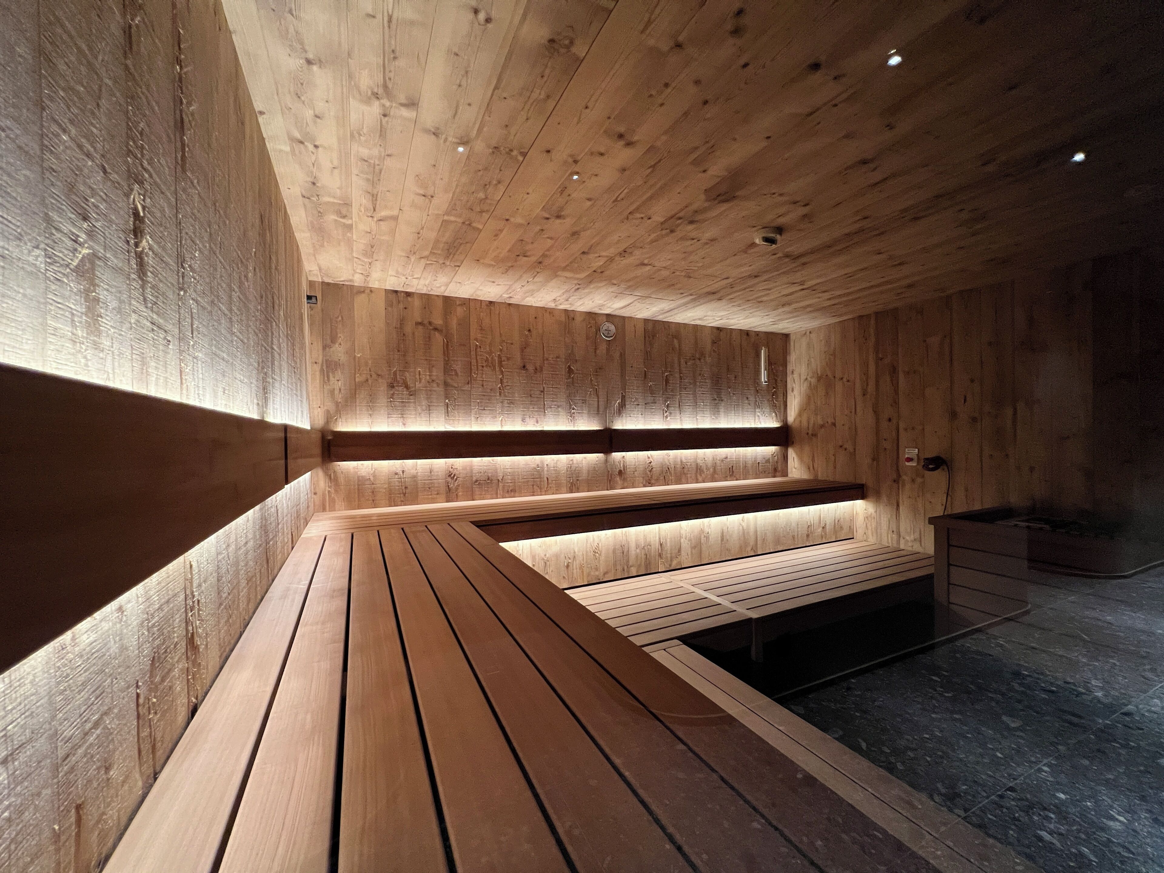Una sauna con bancos de madera y suelo de baldosas.