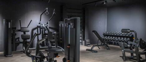 Un gimnasio moderno con diversos equipos de ejercicio, incluyendo una prensa de banca, mancuernas y una estructura para sentadillas.