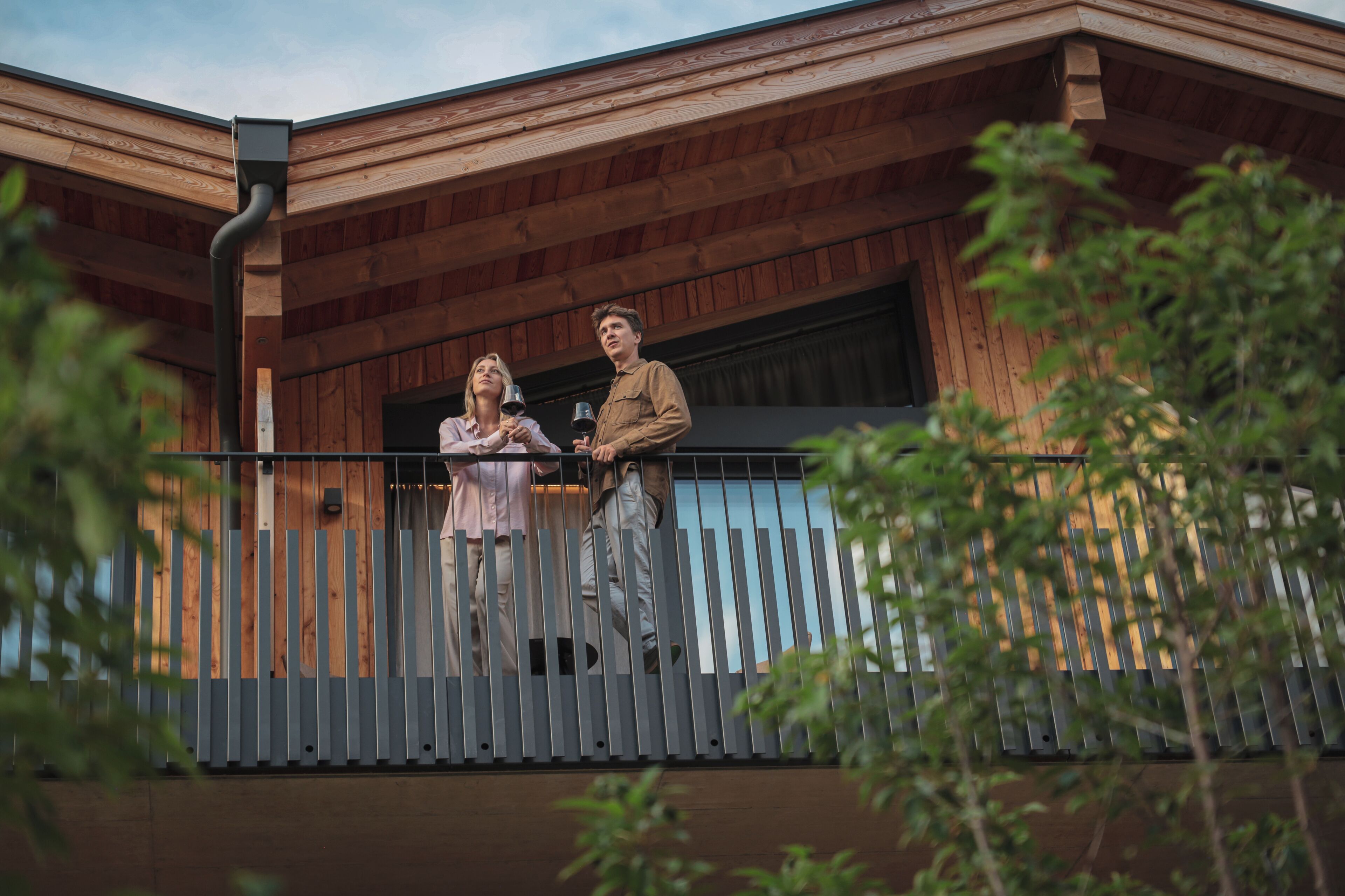 A wooden building with a balcony, a metal railing, and a window.