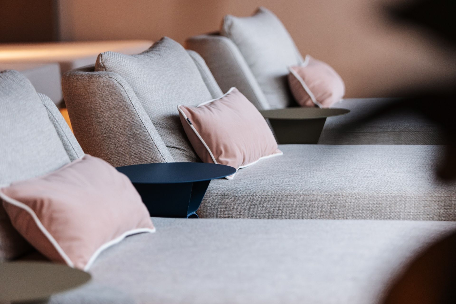 Un salon moderne avec un canapé gris, de nombreux coussins et une table basse ronde.