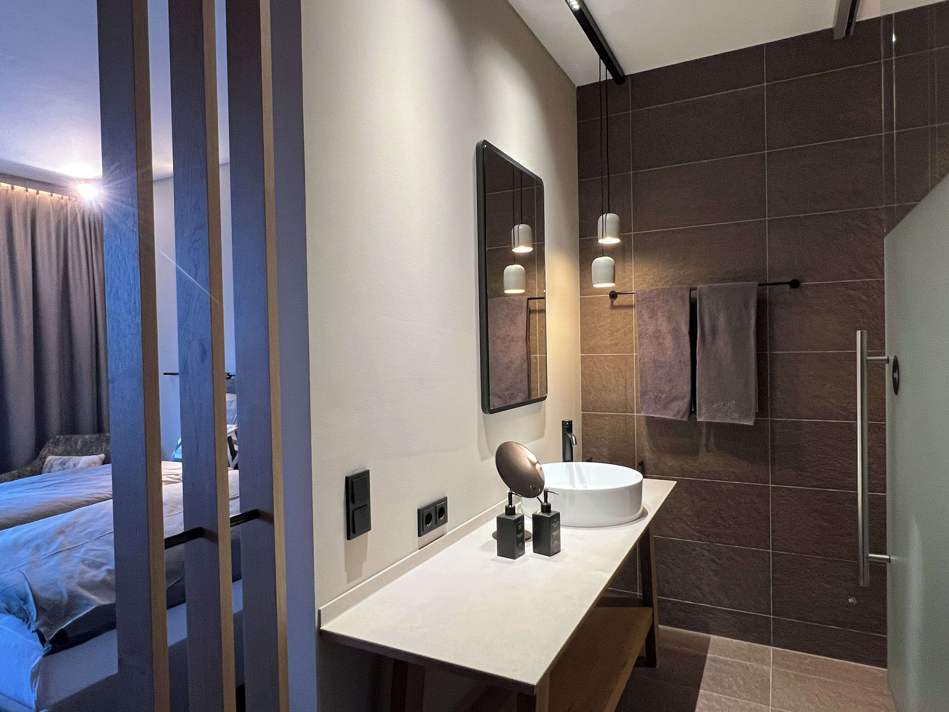 Een moderne badkamer met een grote spiegel, een wastafel en een douchegedeelte.