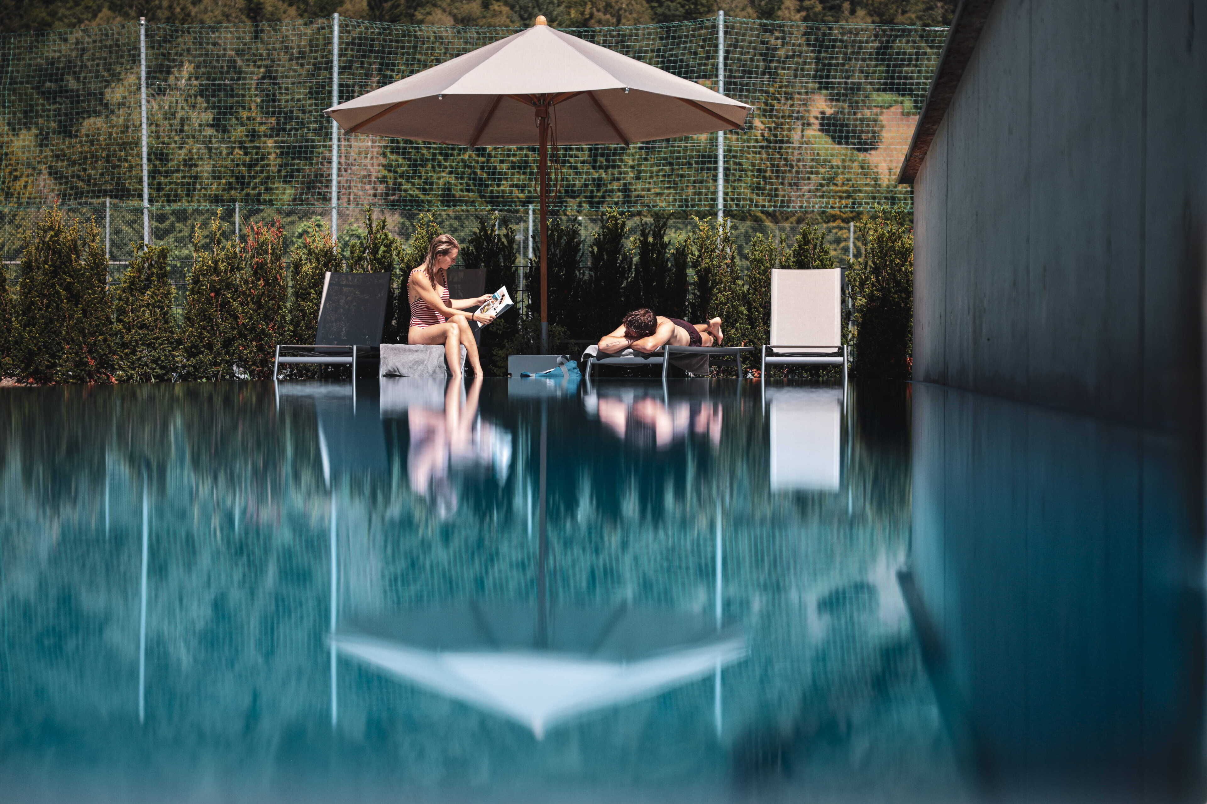 A swimming pool with lounge chairs and an umbrella.
