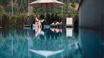 A swimming pool with lounge chairs and an umbrella.