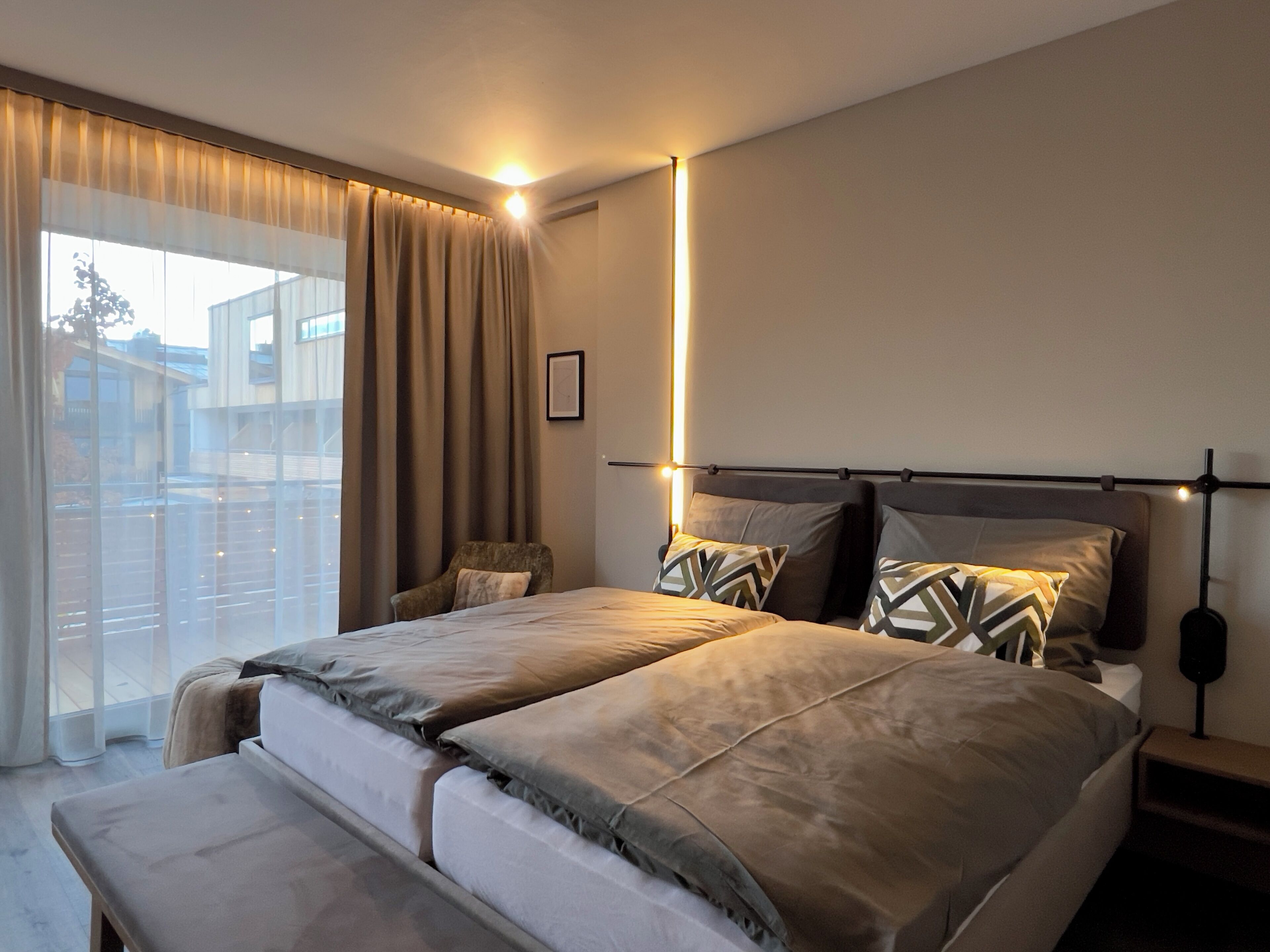 Une chambre à coucher moderne avec un grand lit, une chaise et une table de chevet.