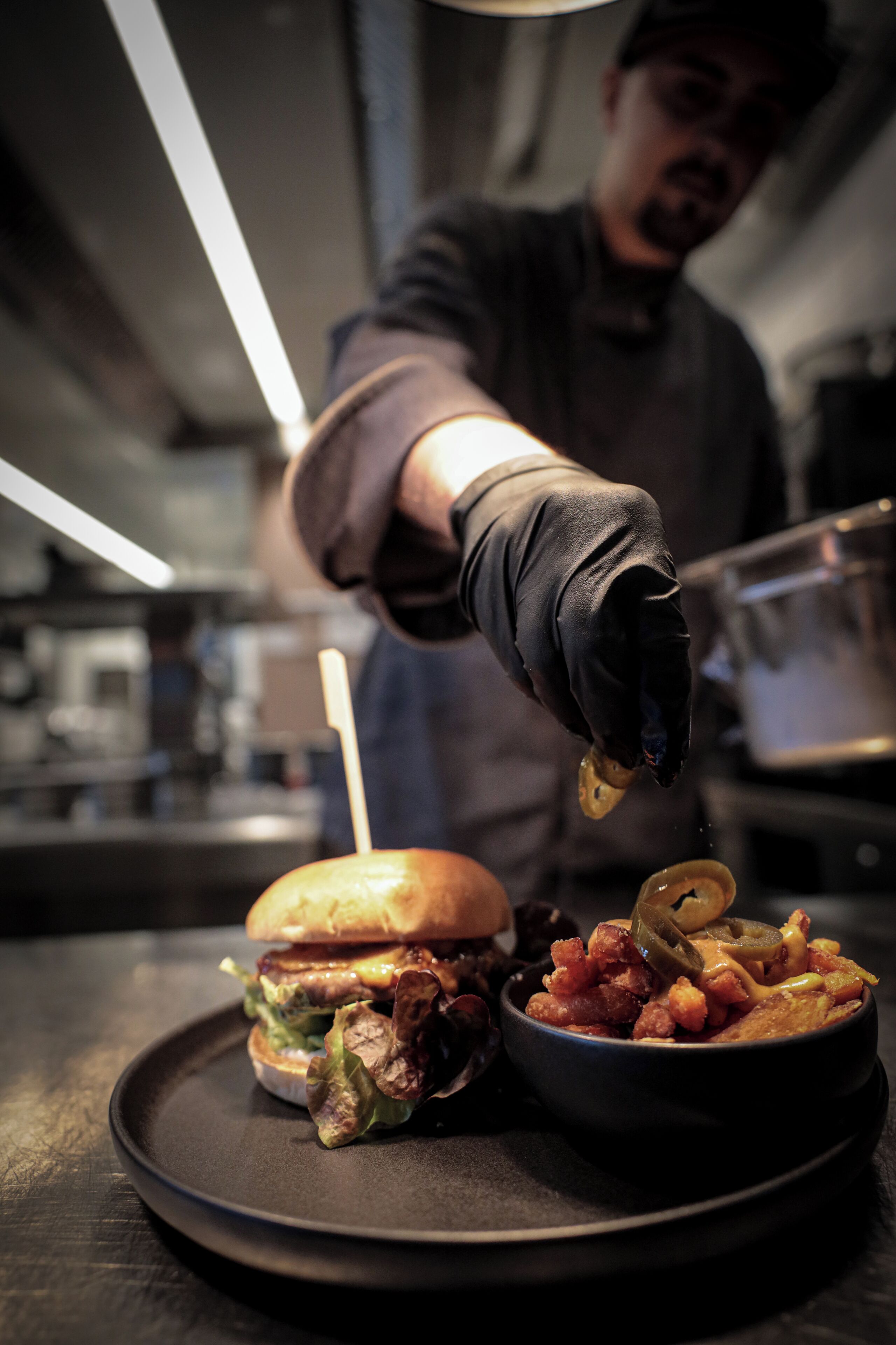 Une personne qui sert de la nourriture, plus précisément un hamburger et un accompagnement, sur un plateau.