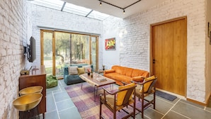 Een moderne woonkamer met een groot raam, een houten deur en een bank.