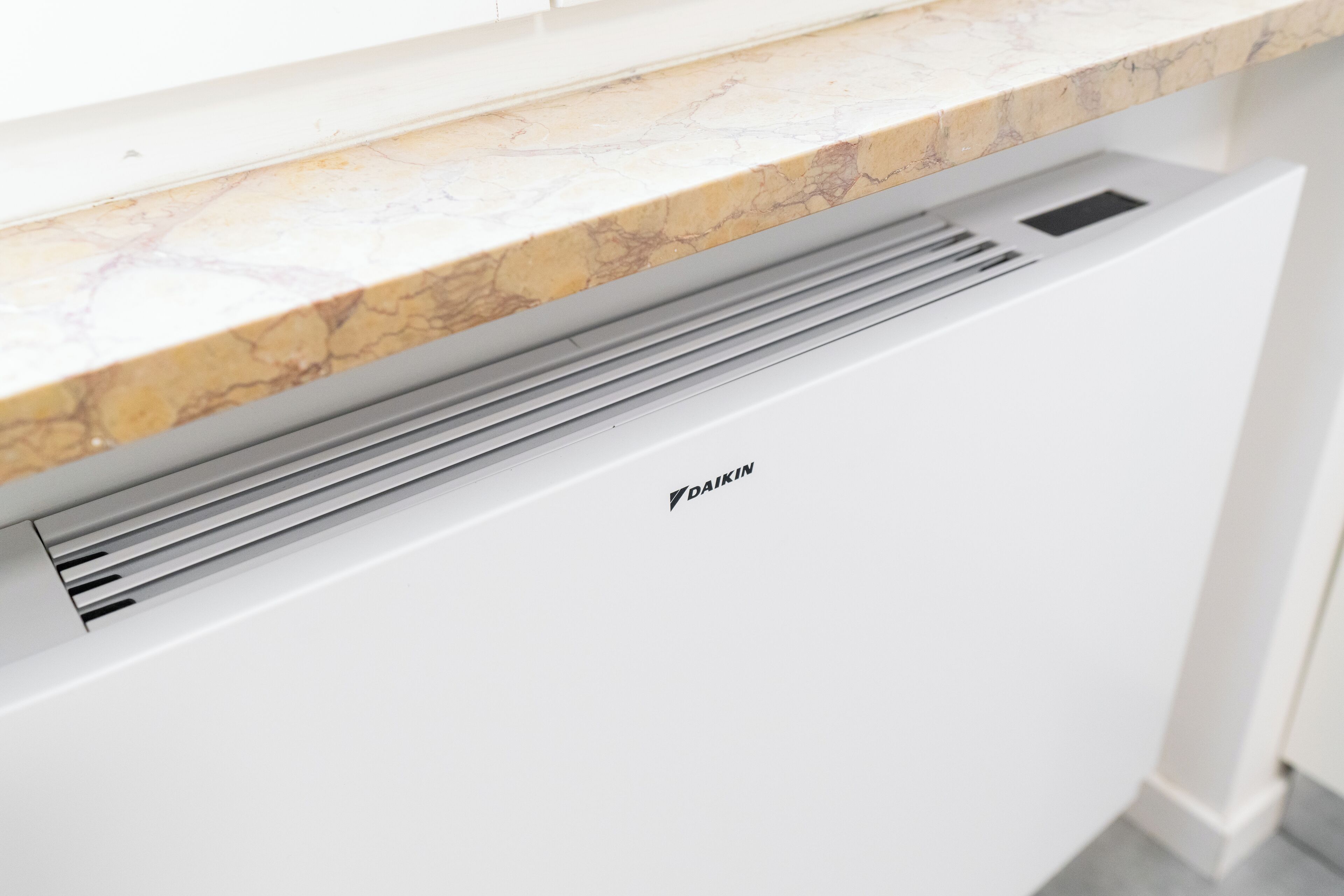 A kitchen with a marble countertop and a Daikin air conditioning unit.