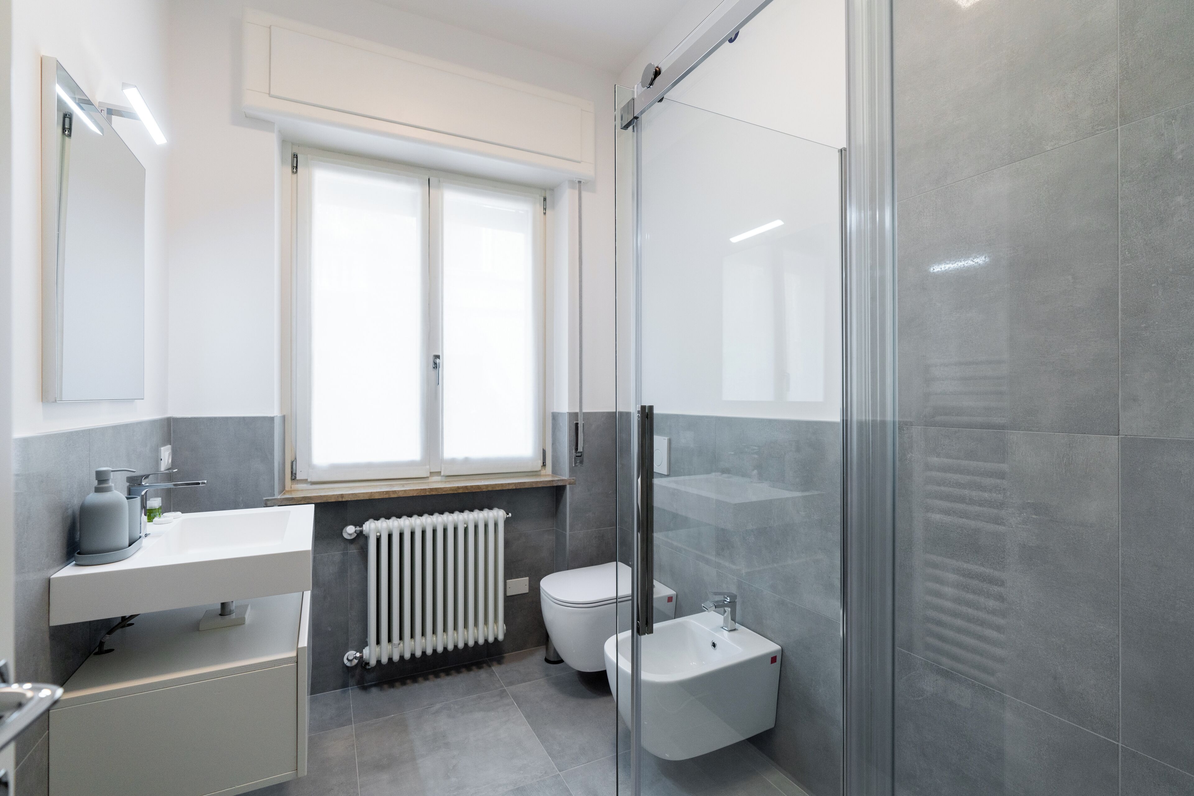 A modern bathroom with a glass shower enclosure, a white sink, and a toilet.