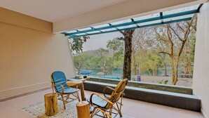 A spacious balcony with wicker furniture, a patterned rug, and a view of a lake and trees. - Silverbill Resorts  (Joida)