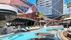 Et moderne hotel med swimmingpool, loungeområder og en markant, geometrisk bygningsfacade.