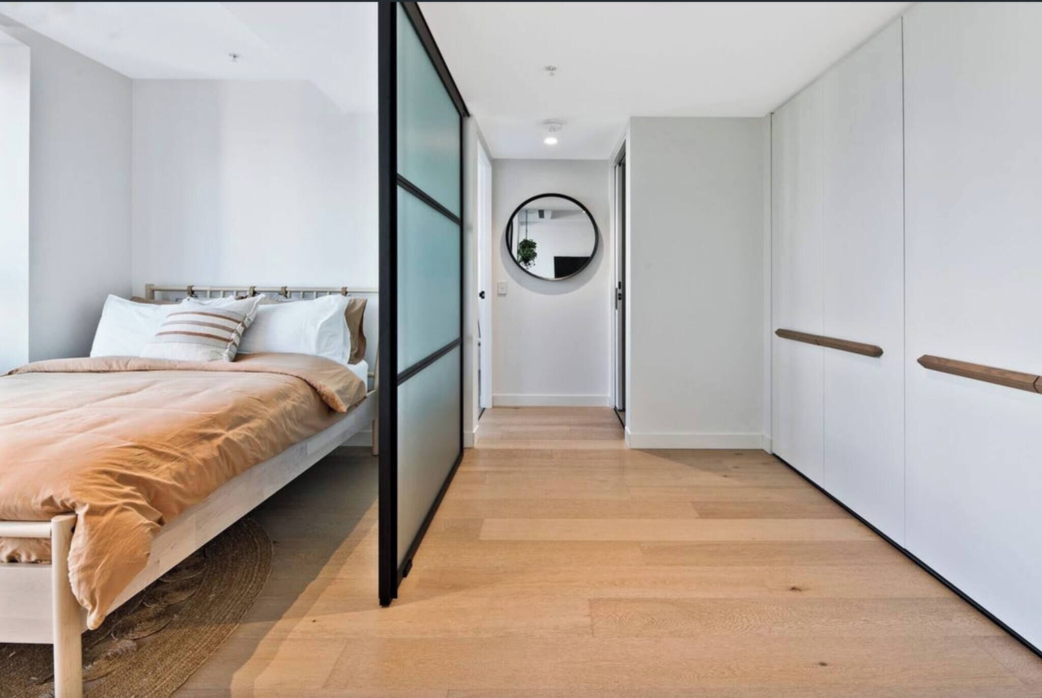 A bedroom with a bed, a bedside table, a mirror, and a wardrobe.