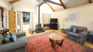 Una sala de estar acogedora con techos altos, chimenea, televisor y sofá.