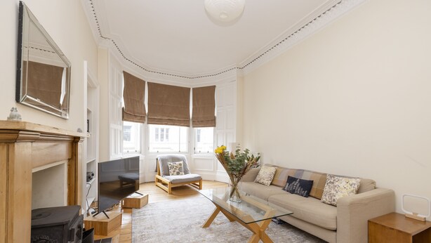 A modern living room with a sofa, a glass coffee table, a fireplace, and a television.