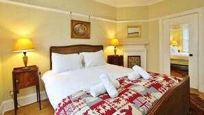 A hotel room with a large bed, two bedside lamps, a fireplace, and a mirror on the wall. - Gorgeous 3-Bedroom Apt Next to Castle & Royal Mile (Edinburgh)
