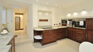 A modern kitchen with a marble countertop, wooden cabinets, and stainless steel appliances. - Gorgeous 3-Bedroom Apt Next to Castle & Royal Mile (Edinburgh)