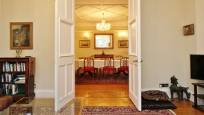 A dining area with a chandelier, a dining table set for six, and a television on the right. - Gorgeous 3-Bedroom Apt Next to Castle & Royal Mile (Edinburgh)