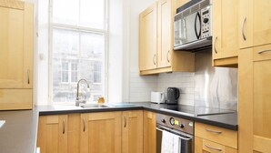 A kitchen with wooden cabinets, a stainless steel oven, a microwave, and a window providing natural light.