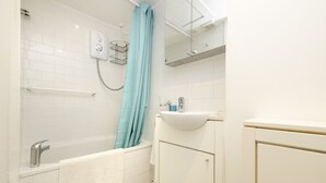 A bathroom with a bathtub, a sink, and a shower curtain.