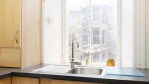 A kitchen with wooden cabinets, a stainless steel sink, and a window with a view of buildings.