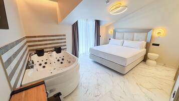 Une chambre d’hôtel moderne dotée d’un grand lit, d’une salle de bain séparée avec un jacuzzi et d’un sol en marbre.