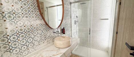 A bathroom with a marble sink, a large mirror, and a shower area with a glass door.