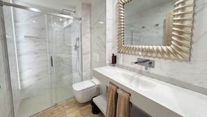 A modern bathroom with a glass-enclosed shower, a white toilet, and a vanity with a large mirror. - Akla Hotel El Burgo de Osma (El Burgo de Osma)
