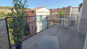 A balcony with a table and chairs, potted plants, and a view of neighboring buildings. - Akla Hotel El Burgo de Osma (El Burgo de Osma)