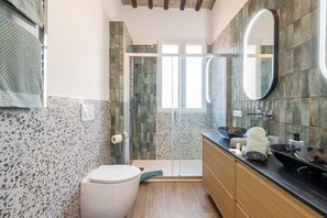 Un baño con ducha, inodoro, tocador y espejo.