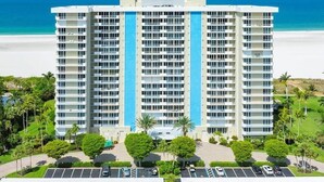 A high-rise hotel with multiple floors, a parking lot, and a beach view. - Beachfront 2BR/2BA condo with pool, Wi-Fi, and ocean views. (Marco Island)