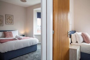A hotel room with a bed, a bedside table, and a window.