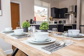 A modern kitchen with dark cabinets, stainless steel appliances, and a dining area set for a meal.