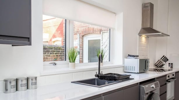 Een moderne keuken met raam, magnetron, spoelbak en fornuis.