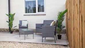 A patio with wicker furniture, a window, and potted plants. - Vacant Nest | The South End | Spacious | Smart TV (Kielder)