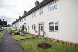 A row of white terraced houses with front gardens, a paved driveway, and a small tree in the front yard. - Vacant Nest | The South End | Spacious | Smart TV (Kielder)