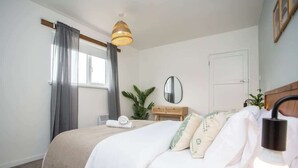 A bedroom with a bed, a bedside table, a mirror, and a hanging light fixture. - Vacant Nest | The South End | Spacious | Smart TV (Kielder)