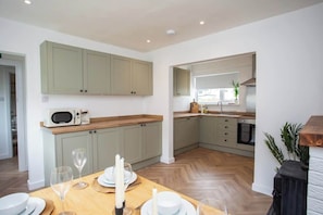 A modern kitchen with light green cabinets, a wooden countertop, and a dining area with a table set for four.