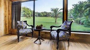 A room with two chairs facing a large window overlooking a grassy area. - Alaya Stays Fortezza | Pet-friendly 6-BHK Farmhouse With Private Pool (Sohna)