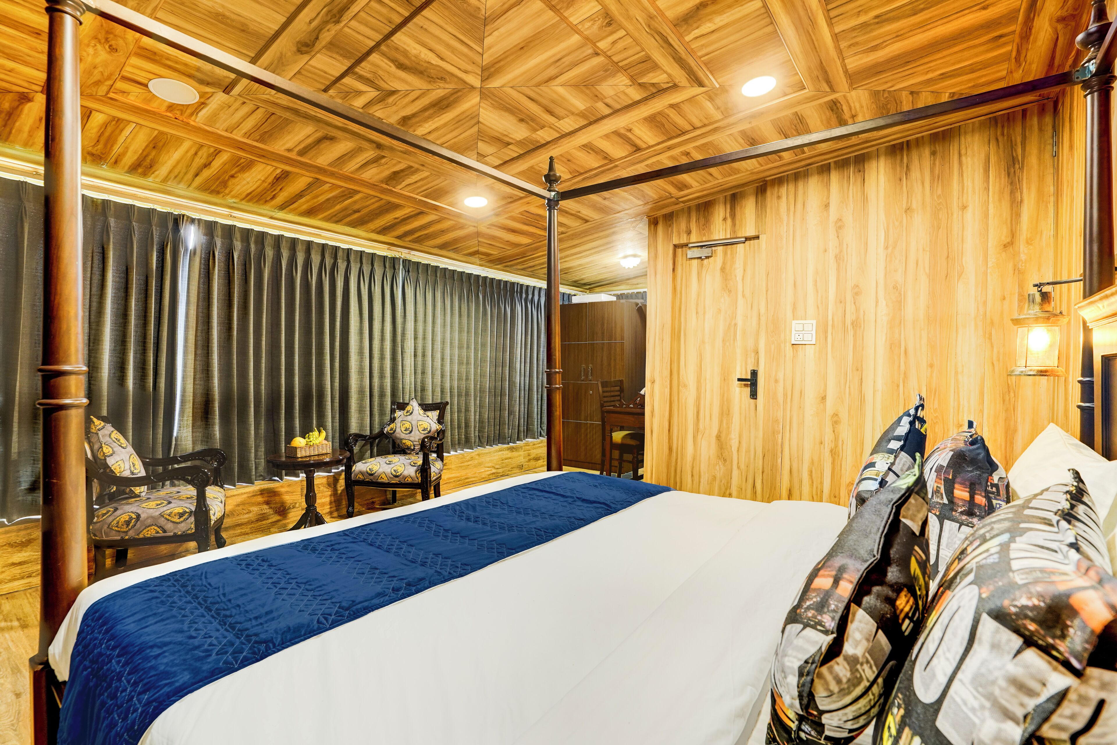 A room with a large bed, wooden ceiling, and a view of a balcony with curtains.