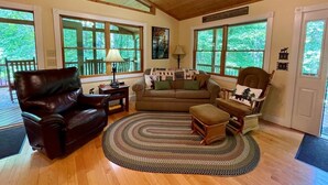 Un salon chaleureux avec un canapé en cuir, un fauteuil en bois et un tapis rond.