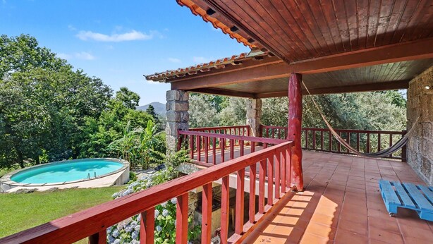 Un espacio al aire libre cubierto con piscina, terraza de madera y hamaca.