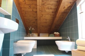 Un baño con vigas de madera, dos lavamanos blancos y una bañera.