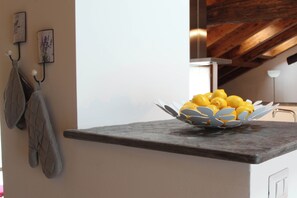Una encimera de cocina con un bol decorativo de limones, un agarradera para horno colgada y un cuadro en la pared.