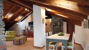 A dining area with a wooden table and chairs, a stone wall, and a green sofa. - Snug Nest (Como)