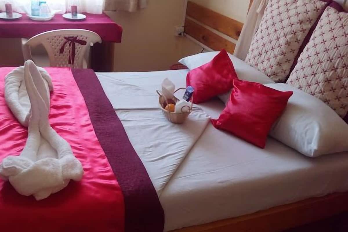 A neatly made bed with a red and white bedspread, a white towel, and a red pillow.
