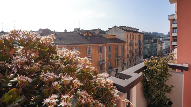 Un balcon orné de plantes en pot, avec vue sur les immeubles.