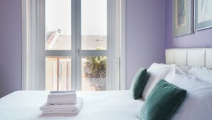 Une chambre d’hôtel avec un lit, des oreillers, une fenêtre et une vue sur les bâtiments et la verdure environnante.
