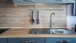 Une cuisine moderne avec un revêtement mural en bois, un évier en acier inoxydable et des ustensiles de cuisine suspendus.