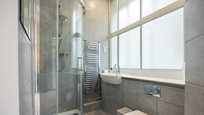 Un baño moderno con cabina de ducha de vidrio, un lavabo blanco y un inodoro.